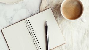 An open journal with a pen and cup of coffee 10 Way to reduce stress naturally